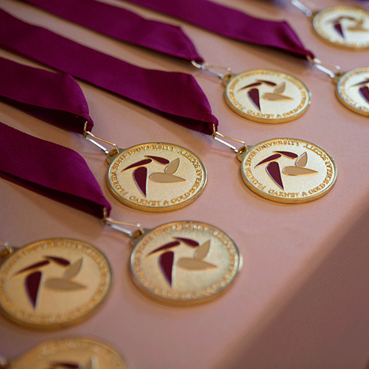 "Garnet & Gold Scholar Society medals on tan tablecloth. Link to FSU News story on Summer 2022 Induction Ceremony."