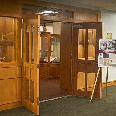 Entryway to FSU Libraries Special Collections & Archives. Entryway, doors and walls are all wooden. Doors are open and there is a diplay easel to the right.