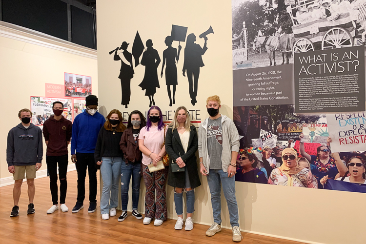Group photo of students who attended Florida History Museum's Exhibit of Florida Women's Activism. Students are standing in front of exhibit in masks.