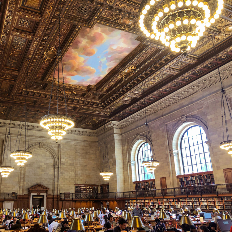 Interior Photo Of New York Public Library with large circular drop down chandeliers. Link to the write up about the Honors Experience Program students who collaborated on a research project under the guidance of Dr. Arianne Johnson Quinn.