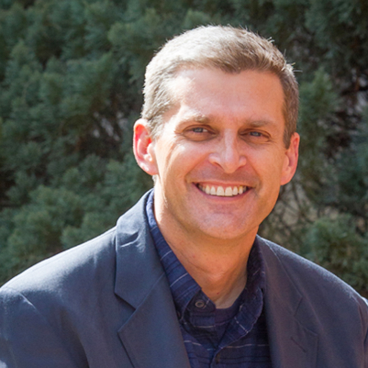 Image of Dr. Jim Dawkins, Associate Professor and Department Chair of Interior Architecture & Design. He served as an Honors in the Major Thesis Director. Professor has short hair, dark blue buttoned-down shirt and gray-blue blazer. He is smiling and has graying light brown hair.