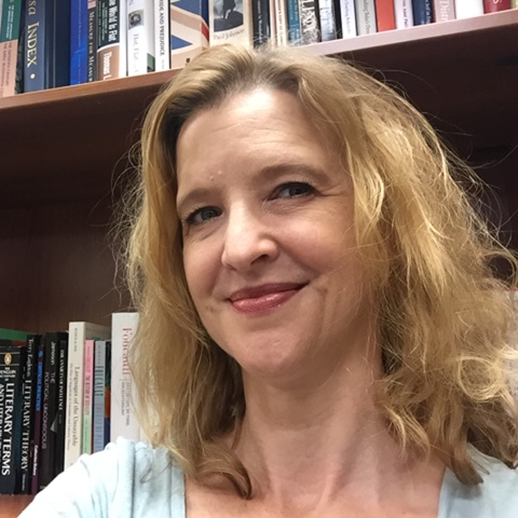 Image of Dr. Leslie Richardson, Honors in the Major Thesis Director for Student, Emily Pacenti. She is affiliated with the Women's Studies Program. Dr. Richardson has medium length blonde hair and is standing in front of a bookshelf. She is wearing a light blue shirt and is smiling.